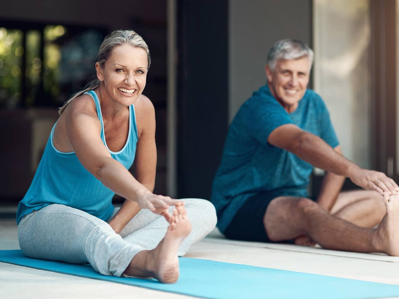 middle aged couple stretching on yoga mats
