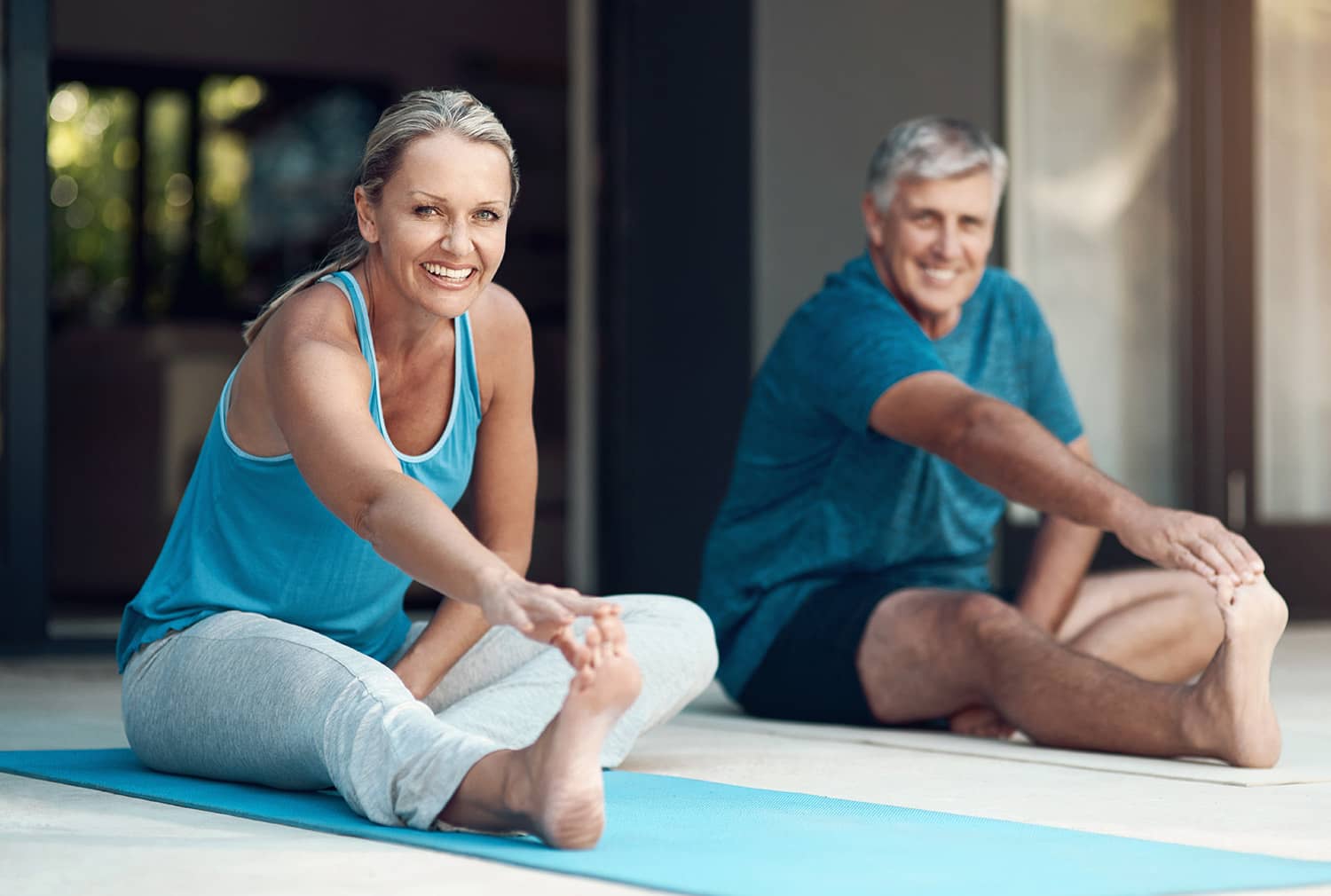 middle aged couple stretching on yoga mats