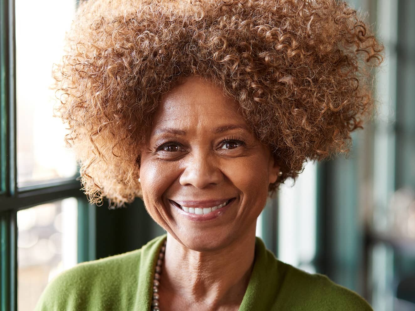 smiling woman with curly hair near window