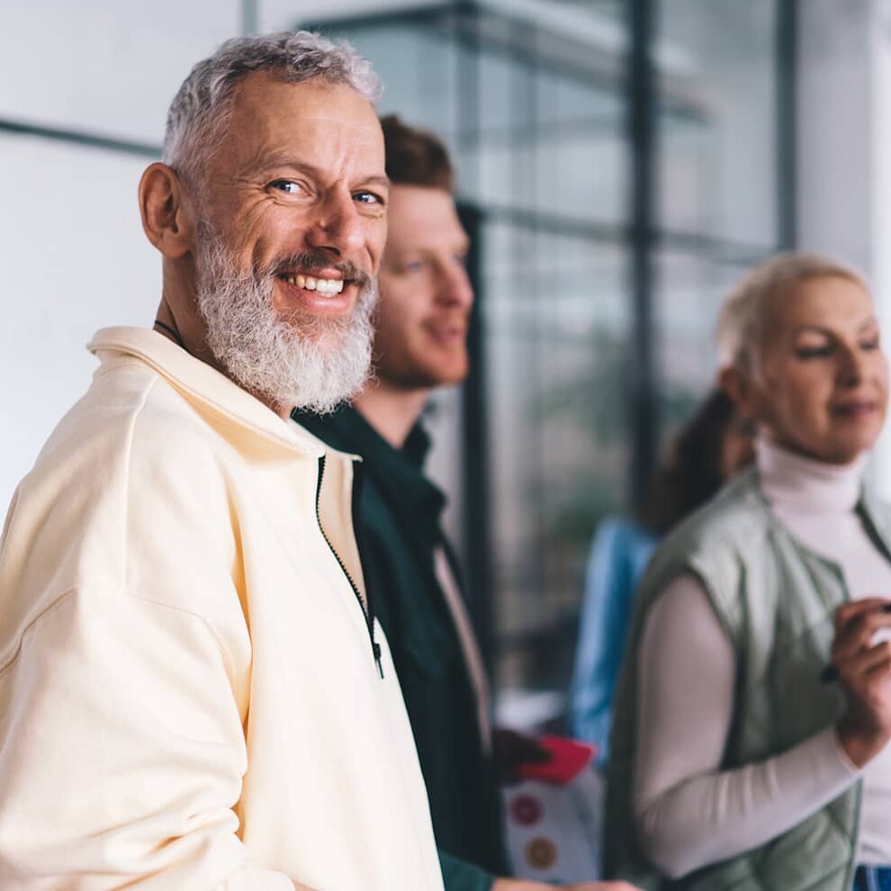 middle aged man in a group turning and smiling at the camera